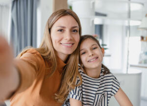 Selfie von Mutter und Tochter, beide lächeln in die Kamera.